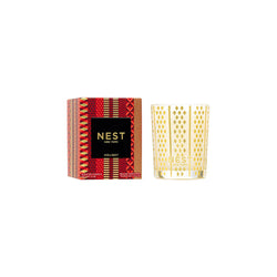 Gold candle and red patterned box with 'NEST' branding on a white background