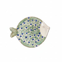 Hand holding a decorative fish-shaped object with green and blue patterns.